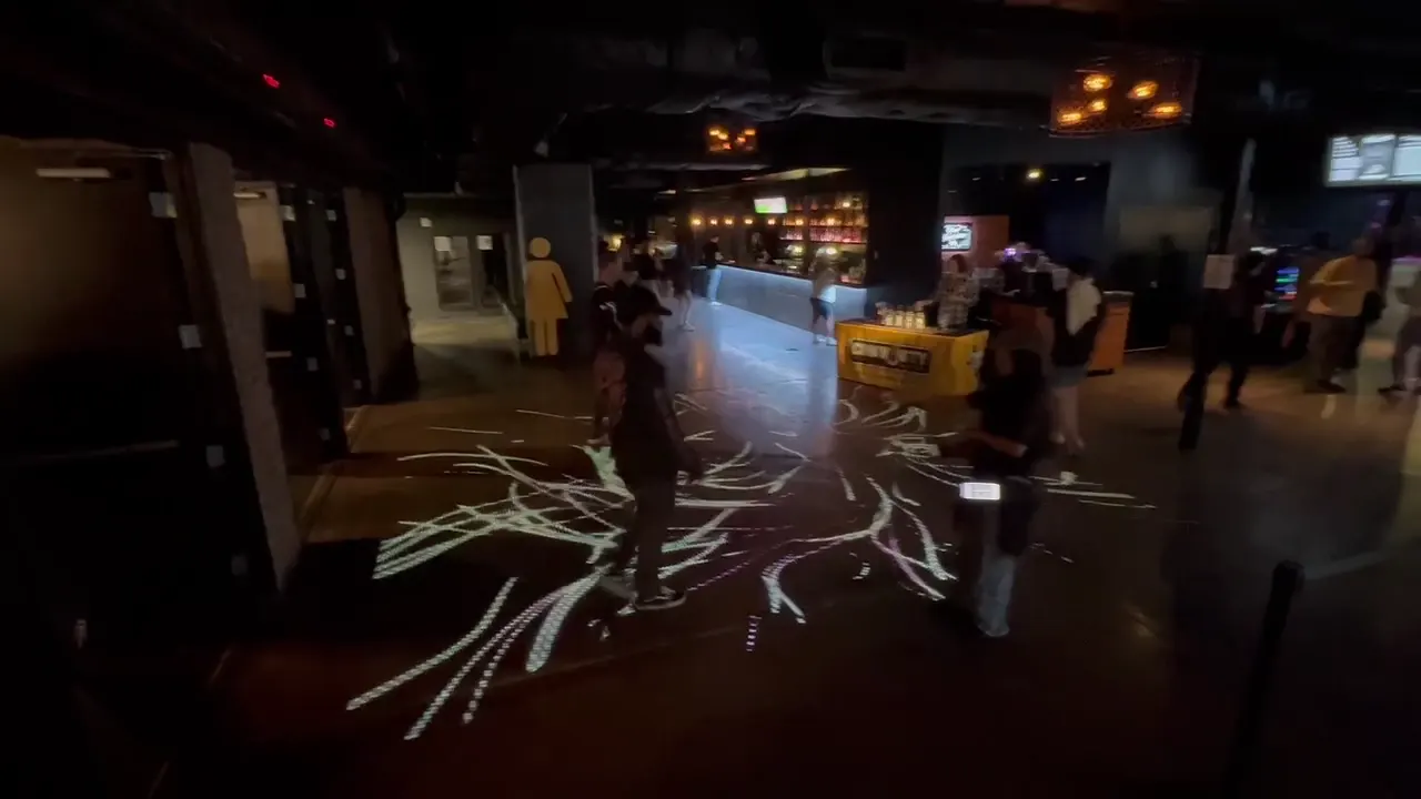 Visitors standing among branching white graphics projected onto the floor.