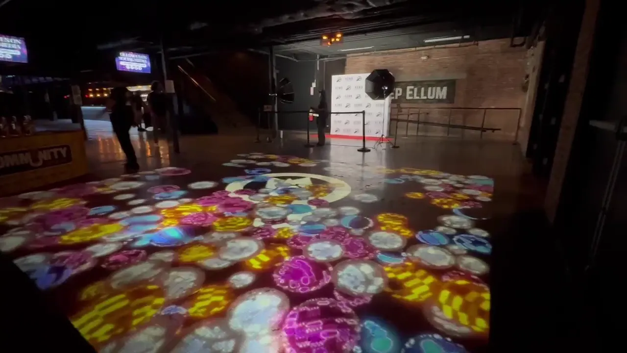 Colorful projected circles in front of the Deep Ellum venue wall.
