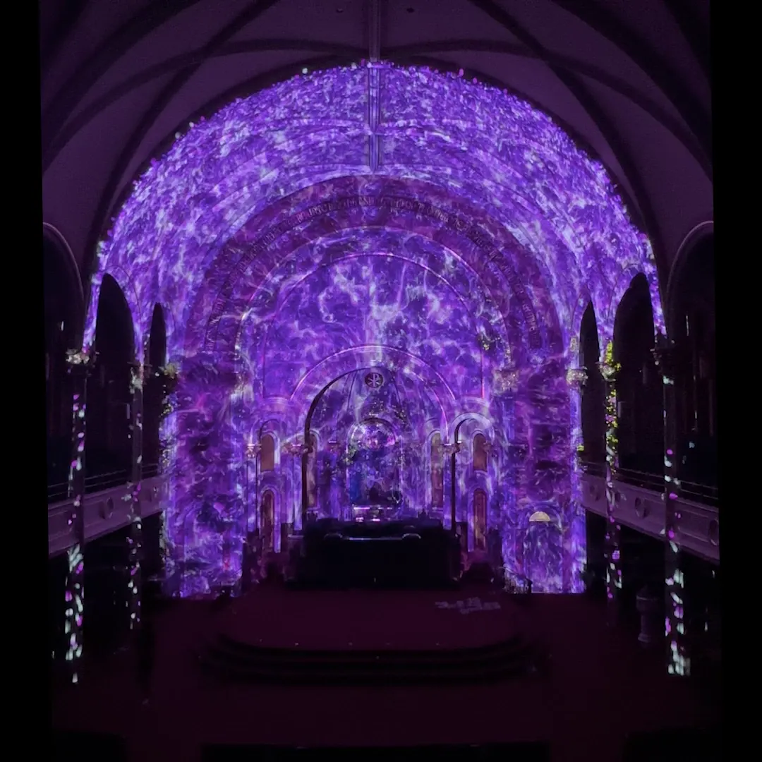Violet textured projection across an arched interior.
